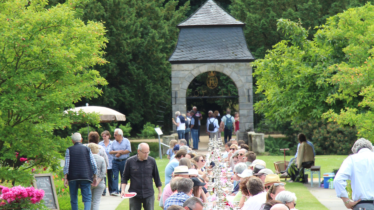 Viele Menschen sitzen an einer Langen Tafel im Park