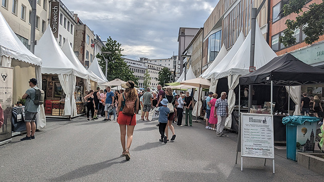 Eine mit Menschen befüllte Straße, links und rechts stehen Austeller des Gourmetfestivals