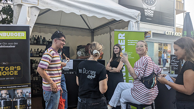 Mehrere Personen stehen an der Redaktionsbar und Trinken Gin-Tonic