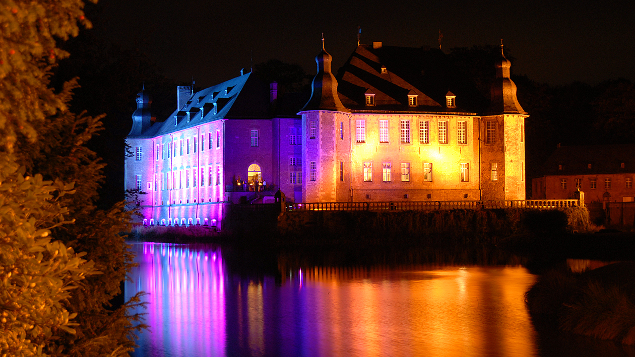 Das Schloss Dyck bunt beleuchtet im dunkeln