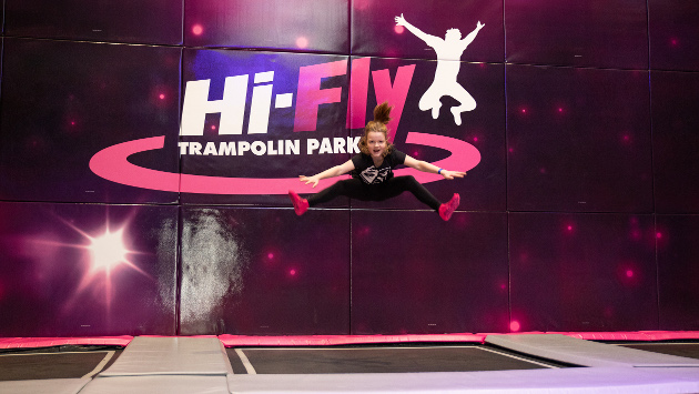 Anke Molitors tochter springt auf einem Trampolin hoch in die Luft, im Hintergrund das Logo vom hi-Fly Trampolinpark