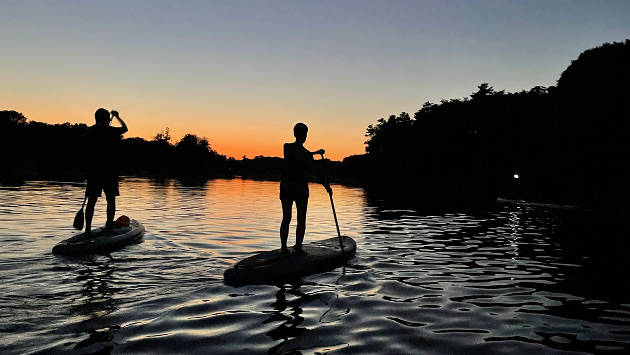 Mehrere Personen SUPen am Hariksee bei Nacht