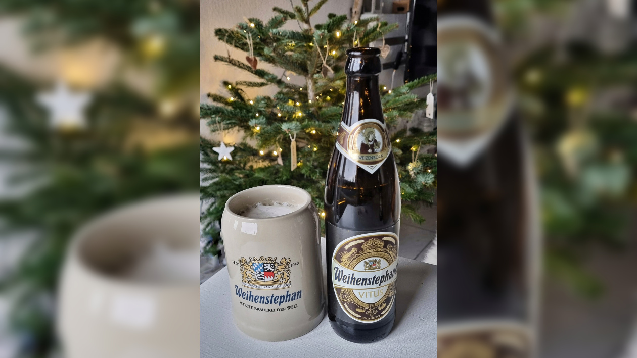 Eine Bierflasche und ein Bierkrug stehen auf einem Tisch vor einem Weihnachtsbaum
