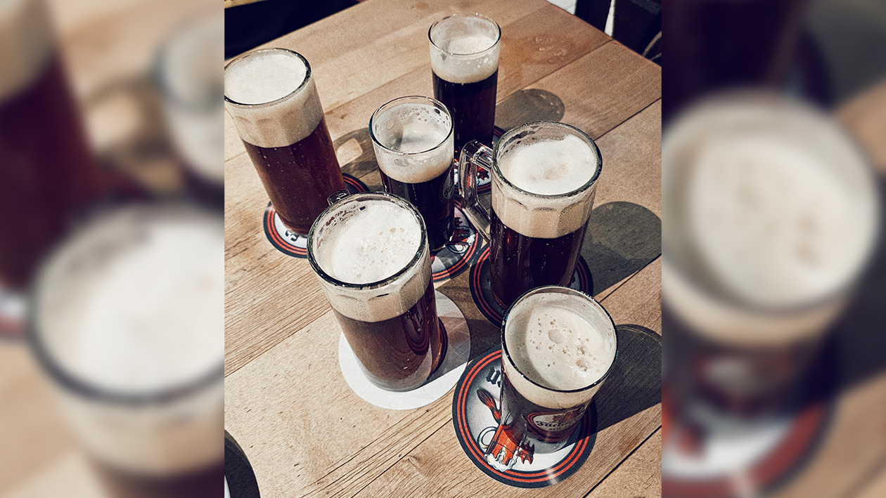 Blick von oben auf sechs Gläser mit dunklem Bier