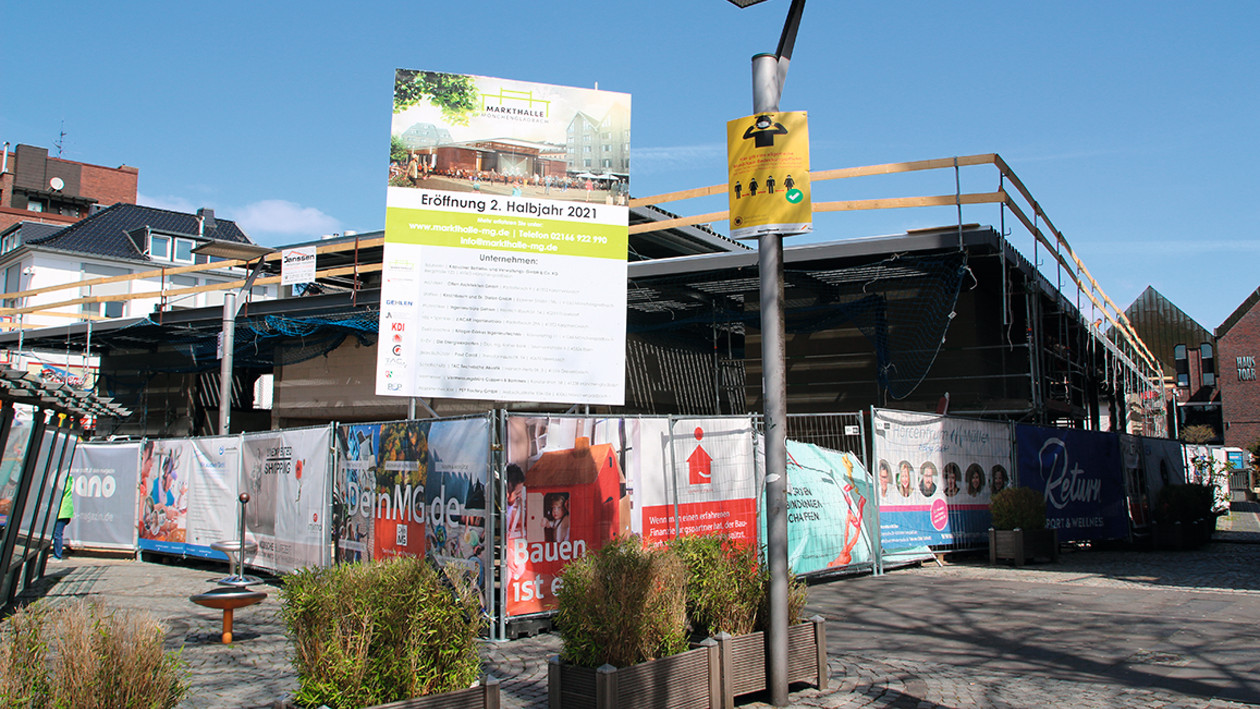 Eine Baustelle, im Vordergrund ein Schild welches die zukünftige Markthalle zeigt.