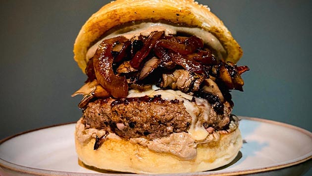 Eine der neuen Burger-Kreationen: Magic Mushroom: Black Garlic Burger mit gebratenen Pilzen, verfeinert mit Thymian, schwarzer Knoblauch-Mayonnaise, überbacken mit Parmesan-Käse und belegt mit karamellisierten Zwiebeln.