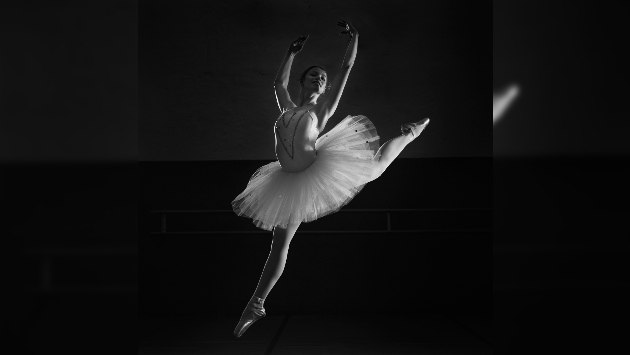 Eine schwarz-weiß Aufnahme einer Balletttänzerin, das Licht schafft hohe Kontraste
