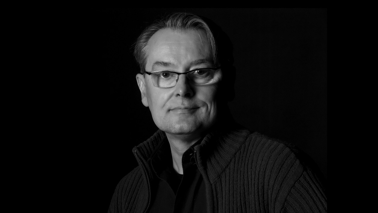 Ein schwarz weiß Portrait von Peter Götz auf schwarzem Hintergrund