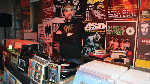 Pete steht hinter einer Theke, auf der Theke stehen viele Schallplatten und ein Schallplattenspieler