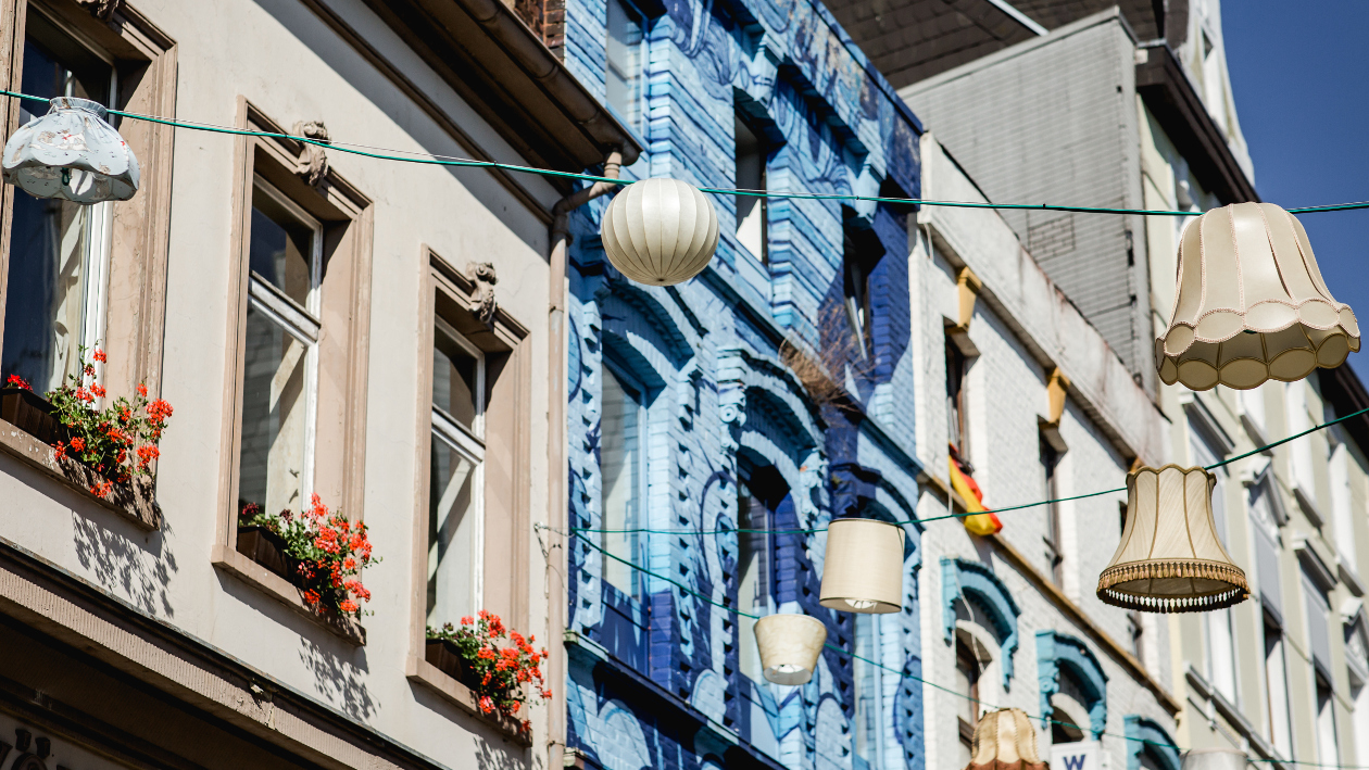 Ein blaues Haus in der Mönchengladbacher Altstadt, davor aufgehangende Lampenschirme als Beleuchtung und Deko.