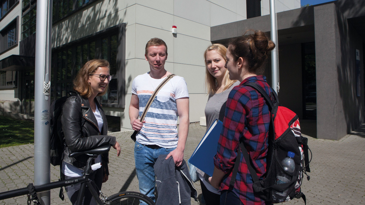 3 Studiernede der Hochschule Niederrhein stehen auf dem Campusgeländer Mönchengladbach