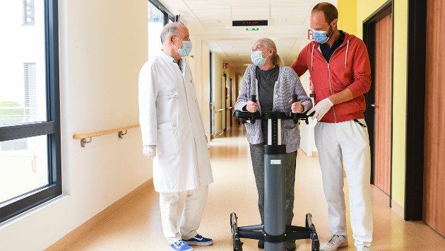 Chefarzt Dr. Jaeger der Geriatrie am Elisabeth Krankenhaus Rheydt geht mit mit einer Patientin über den Flur, neben der Patientin geht ein Pfleger