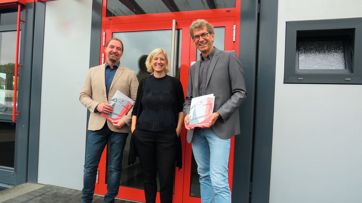 Peter Settele, Stefanie Neumann und Matthias Merbecks stehen vor einer roten Tür.