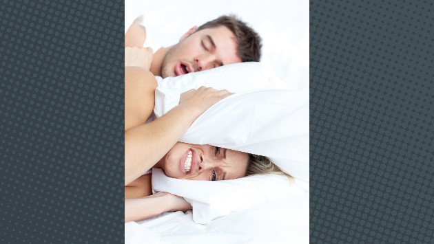 Eine Frau und ein Mann liegen im Bett, die Frau drückt sich das Kissen aufs die Ohren