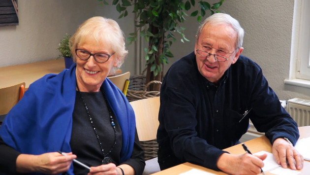 Zwei Senioren sitzen an einem Tisch und lernen