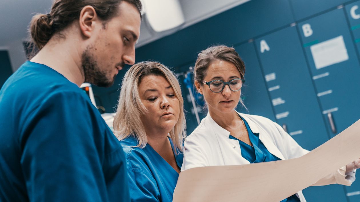 Dr. Annika Stollenwerkund zwei personen aus ihrem Team schauen in Patientenakten