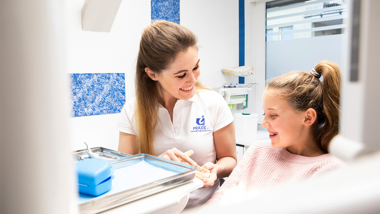 Dr. Isabelle Grünewald spricht mit einem Mädchen während einer Behandlung
