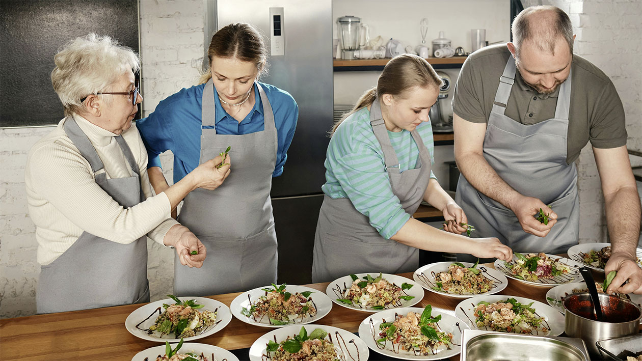 Gruppe von drei Frauen und einem Mann bereiten Essen zu