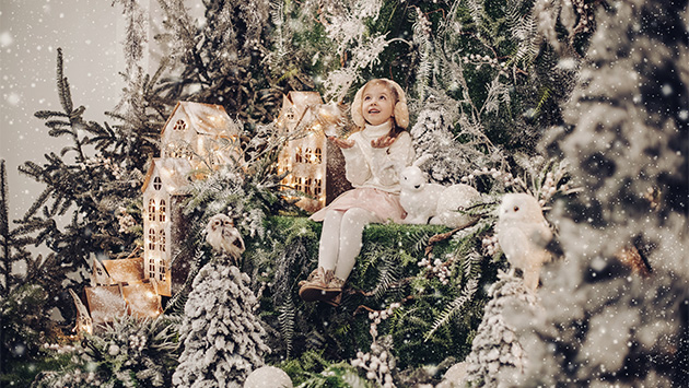 Ein lächelndes Kind sitzt inmitten weihnachtlicher Atmosphäre