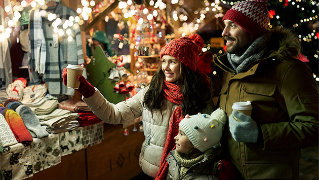 Eine Familie steht an einem Stand auf einem Weihnachtsmarkt
