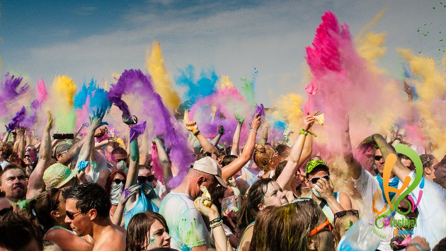 Viele Menschen feiern auf dem Holifestival, es fliegt viel Farbpulver durch die Luft
