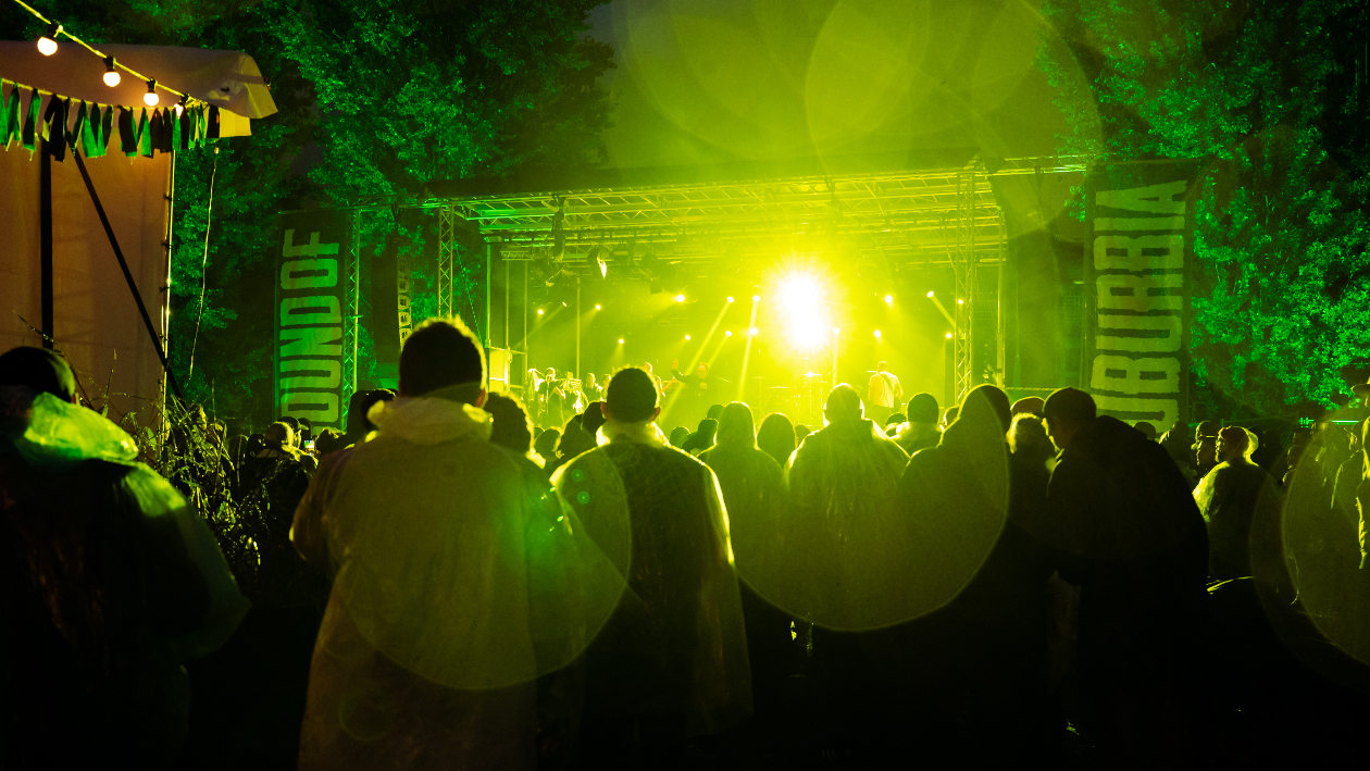 Viele Menschen stehen vor einer grün beleuchteten Bühne auf dem Sound of Suburbia Festival