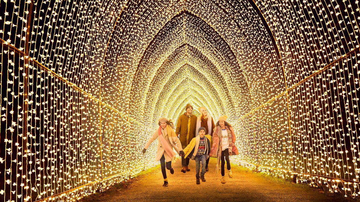 Eine Familie läuft durch einen mit Lichterketten beleuchteten Gang